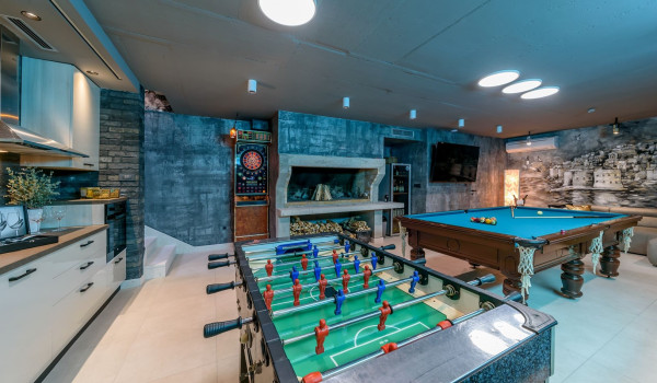 Modern kitchen, darts, table football, pool table and LCD TV in the comfortable entertainment room in the basement of the luxury villa with pool near Split.