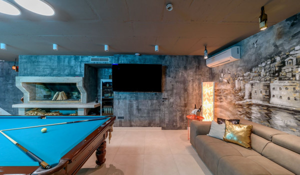 Wood-burning fireplace next to LCD TV in the entertainment room in the basement of the modern villa Velvet Bourbon Split