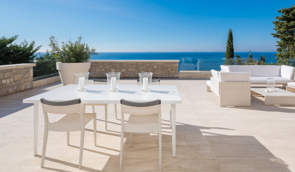 Outdoor terrace with a panoramic view of the sea, a dining table and chairs and a sofa set in a luxury villa for rent in Primosten