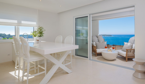 A dining table with chairs and an exit to the balcony with sea view of Croatia luxury holiday villa