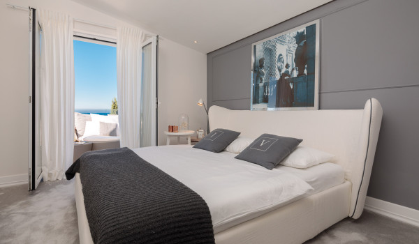 A spacious bedroom with a double bed and access to the balcony with a sofa in the luxury Croatia villa for rent Primosten Glamour