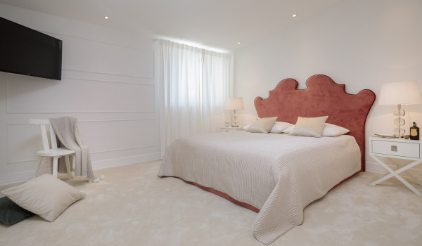 A spacious bedroom of Croatia luxury pool villa with double-size bed and an LCD TV, as well as a sitting and resting area