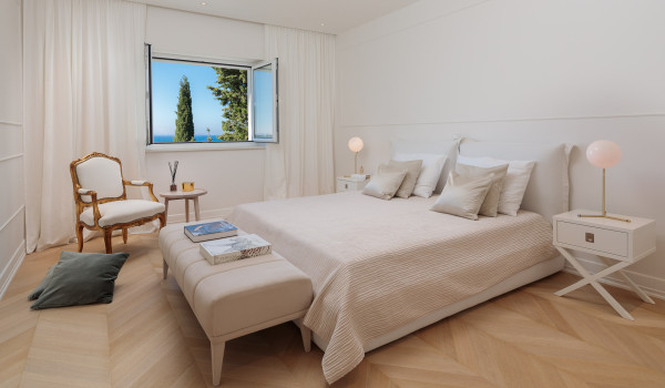 A bedroom with a comfortable double bed, a stool and a place to sit and relax with an armchair in a luxury Croatia villa with a private pool in Primosten