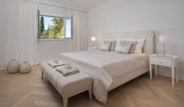 A spacious bedroom of Croatia luxury family villa with double-size bed and a stool for rent with private pool in Primosten