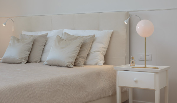 A view of a double bed decorated with pillows next to a table with a night lamp in the bedroom of Croatia luxury villa in Primosten