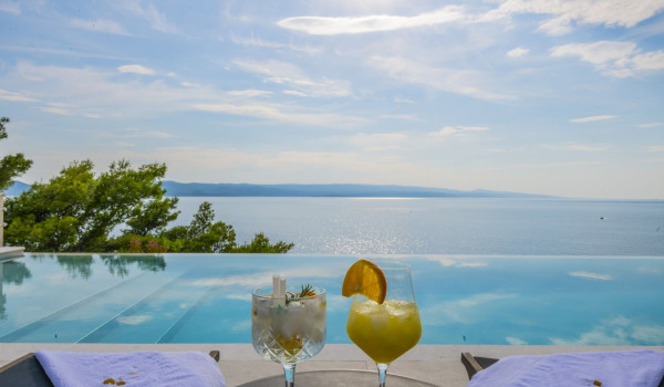 View of the private heated pool and the sea from the outdoor terrace with a sunbed in the Croatian luxurious villa Glorious Brela in Brela