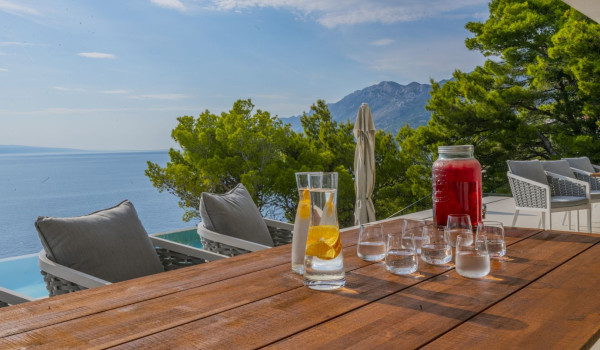 Refreshing juice served on a wooden table on the outdoor terrace with a sea view in the luxurious villa Glorious Brela in Brela