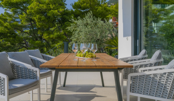 A sitting and resting area with a table where wine is served and chairs on the outdoor terrace of a modern villa for rent and vacation in Brela