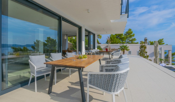 A view of the covered outdoor terrace with a dining table and chairs and a direct entrance to the interior of the luxurious villa for rent Glorious Brela in Brela