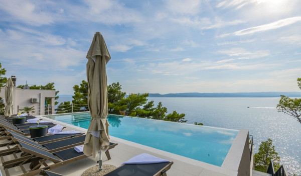 Sunbeds on the outdoor terrace next to the private pool with a sea view in the luxury pool villa Glorious Brela in Brela