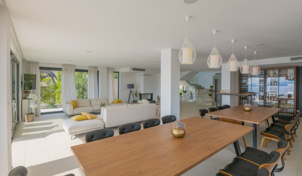 Dining table with chairs and living room with sofa and LCD TV in a luxury rental villa with private sauna in Brela