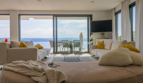 View from the living room to the outdoor terrace with a seating area and a sea view in a modern villa with a private gym in Brela