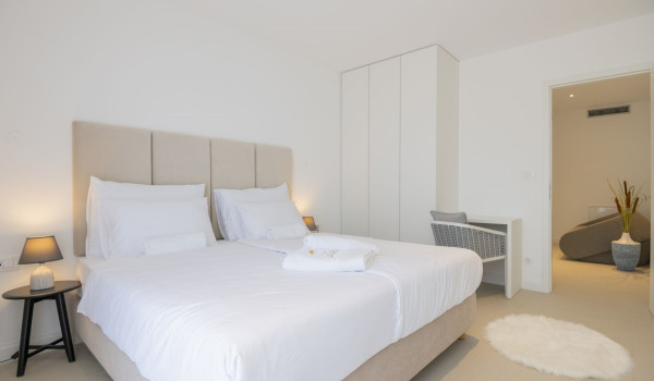 A spacious bedroom with a comfortable bed, a large wardrobe and a desk with a chair in a modern villa for a family holiday in Brela