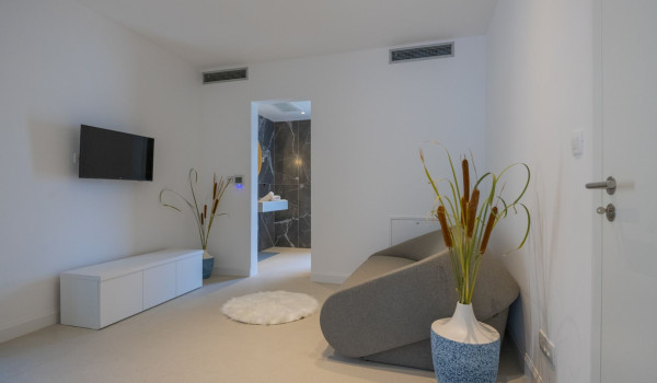 Space for sitting and relaxing with a comfortable sofa, LCD TV and an entrance to the en suite bathroom in a modern villa by the sea in Brela