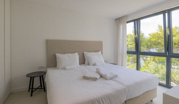 A bedroom with a double bed and a view of the greenery and the sea in the luxurious villa with a private pool Glorious Brela in Brela