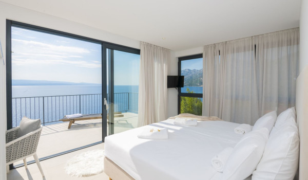 A bedroom with a double bed and a private balcony with a sun lounger in a villa with a private pool in Brela