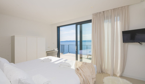 Double bed, wardrobe and LCD TV in the bedroom with its own exit to the balcony in the modern villa by the sea Glorious Brela in Brela