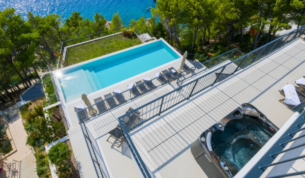 A view of the outdoor terraces of the luxurious villa Glorious Brela in Brela, where there is a jacuzzi, deckchairs and a private pool with a view of the sea