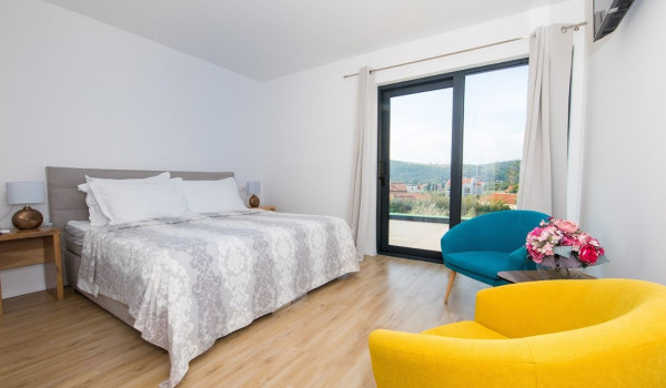 King size bed and seating area in a bedroom of a luxury villa Quiet Land with private pool and badminton court near Dubrovnik