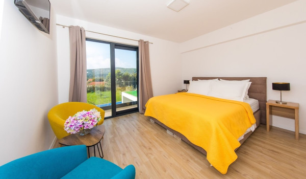 Bedroom with double bed, armchairs and access to the balcony in the luxury villa Mlini Quiet Land near Dubrovnik with concierge service and parking